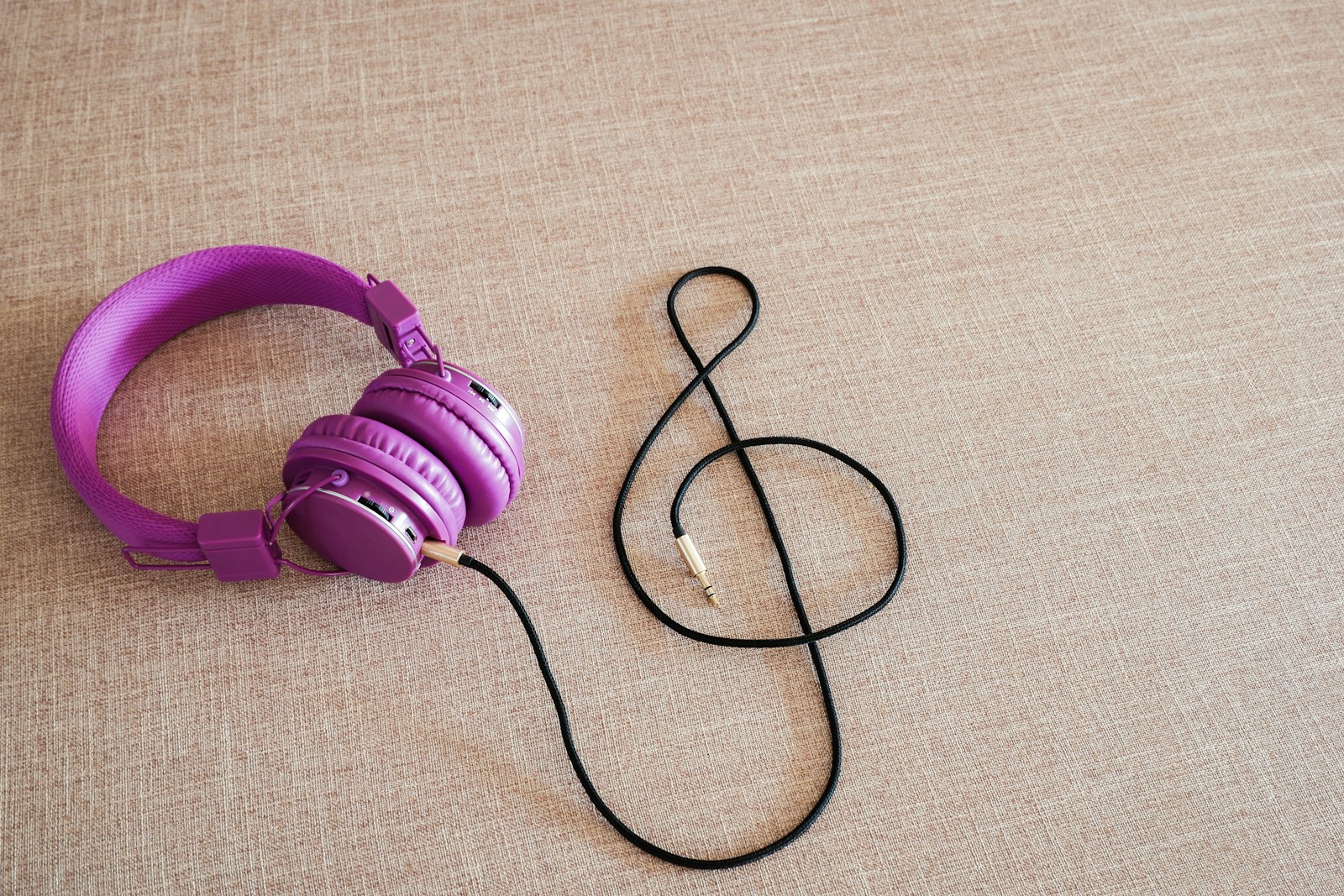 Purple headphones next to a treble clef symbol.